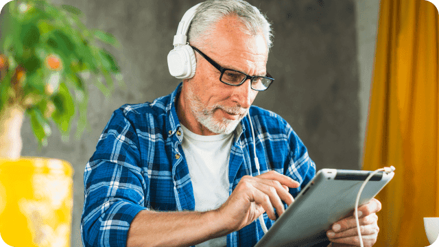 senhor estudando com fone de ouvido e tablet nas mãos