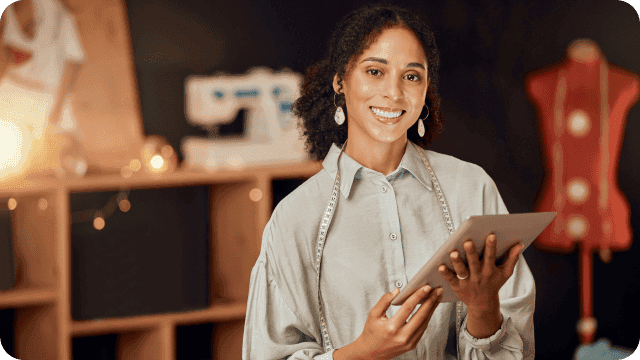 jovem costureira MEI sorridente em seu ateliê