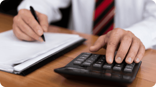 mãos masculinas usando calculadora e escrevendo num papel
