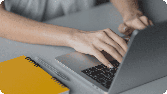 Mãos femininas digitando no teclado de um notebook