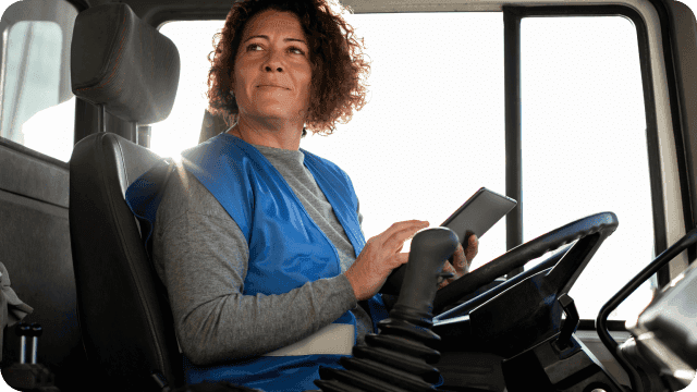 Mulher, ao volante de um caminhão estacionado, com tablet nas mãos