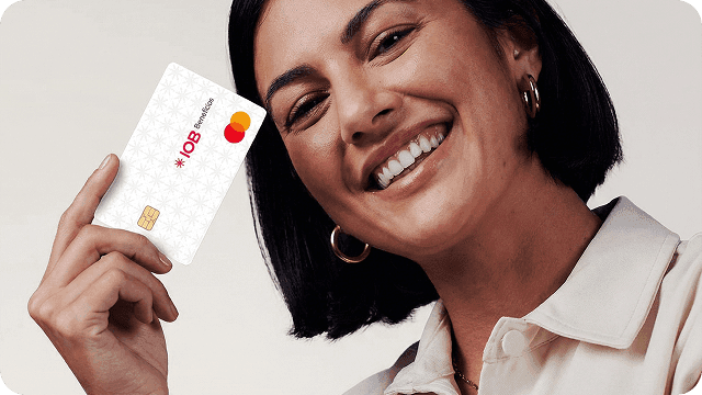 Jovem mulher sorridente segura o cartão IOB Benefícios